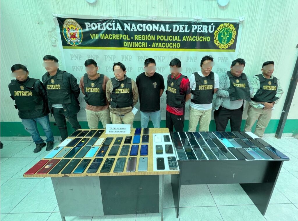 Ocho hombres detenidos frente a una mesa con 77 celulares recuperados, en un operativo policial en Ayacucho, Perú.